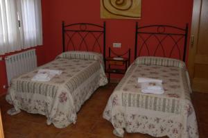 two beds in a room with red walls at Casa Mariví in Niembro