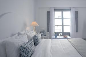 a white bed with blue pillows in a bedroom at Antoperla Luxury Hotel & Spa in Perissa