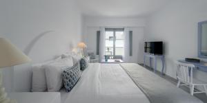 a white room with a bed and a television at Antoperla Luxury Hotel & Spa in Perissa