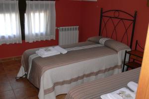 two beds in a room with red walls at Casa Mariví in Niembro +6 photos