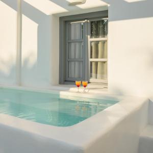 two glasses of wine sitting next to a swimming pool at Antoperla Luxury Hotel & Spa in Perissa