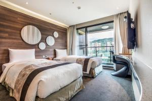 2 łóżka w pokoju hotelowym z oknem w obiekcie Green World SongShan w Tajpej