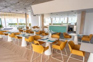 a restaurant with white tables and yellow chairs at Hotel Taimar in Costa Calma