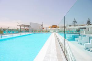 a swimming pool with blue chairs in a building at Hotel Taimar in Costa Calma