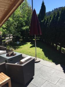 eine Terrasse mit einem Sonnenschirm, einem Sofa und einem Tisch in der Unterkunft Ferienwohnungen Weidach in Oberstdorf