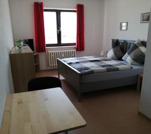 a bedroom with a bed and a table and a window at Pension Zur alten Fachschule in Triptis