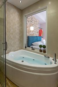 a bath tub in a bathroom with a bedroom at Erotokritos City Luxury Suites in Rethymno +52 photos