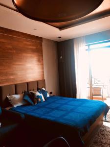 a bedroom with a blue bed with a large window at MISS Premier 19 Milmari in Kopaonik
