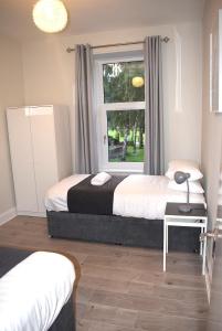 1 dormitorio con 2 camas y ventana en Kelpies Serviced Apartments- Victoria en Falkirk