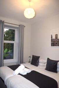 two beds in a bedroom with a window and a chandelier at Kelpies Serviced Apartments- Victoria in Falkirk