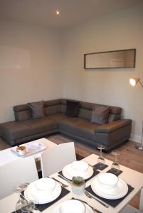 a living room with a couch and a table with plates on it at Kelpies Serviced Apartments- Victoria in Falkirk