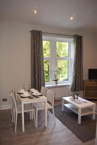 comedor con mesa, sillas y ventana en Kelpies Serviced Apartments- Victoria en Falkirk
