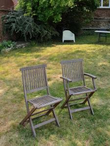 two wooden chairs sitting in the grass in a yard at Studio, chambres, appartement, gite in Vendegies-sur-Écaillon