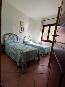 a bedroom with two beds and a window at Villetta Sterlizia in San Teodoro