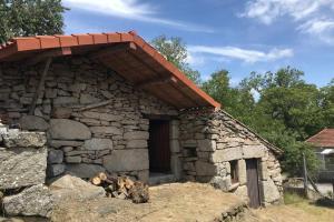 um pequeno edifício de pedra com telhado vermelho em CASA ALBA DE SAN ROMÁN em Ourense