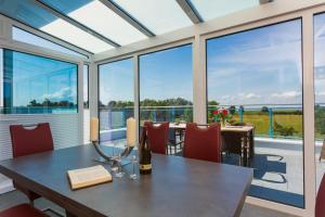a dining room with a table and chairs and large windows at Appartementhäuser Achterwasserblick in Ostseebad Koserow