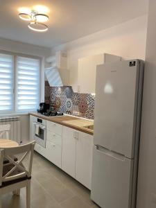 eine weiße Küche mit einem Kühlschrank und einem Tisch in der Unterkunft Mia Apartament in Tulcea