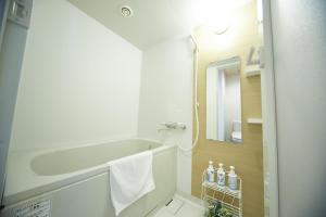a bathroom with a tub and a sink and a mirror at Izumisano Center Hotel Kansai International Airport in Izumi-Sano