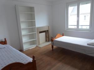 een slaapkamer met 2 bedden en een open haard bij gîte iaorana - maison en centre ville in Valognes