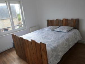 een slaapkamer met een bed met een houten hoofdeinde en een raam bij gîte iaorana - maison en centre ville in Valognes