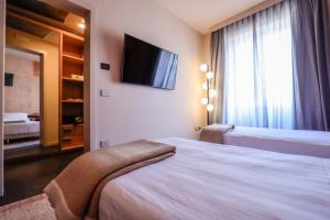 a hotel room with a bed and a flat screen tv at Arco Vecchio Urban Suite - Epoca Collection in Lecce