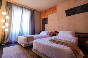 ein Hotelzimmer mit zwei Betten und einem Fenster in der Unterkunft Arco Vecchio Urban Suite - Epoca Collection in Lecce