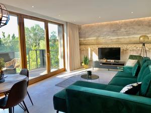 ein Wohnzimmer mit einem grünen Sofa und einem TV in der Unterkunft Baltic Riviera Apartments - Garden Sanctuary Retreat in Danzig