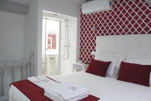 a white bed with white pillows and pillows next to a window at ÍSIS Guest House in Braga