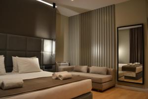 サランダにあるArtNest Luxury Hotel & Suitesのベッドルーム(ベッド1台、ソファ、鏡付)