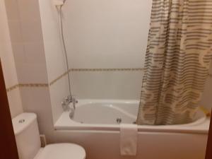 a bathroom with a tub and a toilet and a tub and a shower curtain at Clube Meia Praia in Lagos
