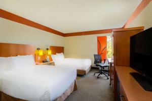 a hotel room with two beds and a flat screen tv at CLT Airport Inn & Suites in Charlotte