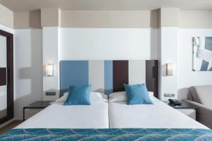 a bedroom with two beds with blue pillows at Hotel Riu Costa del Sol - All Inclusive in Torremolinos