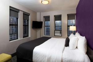 a hotel room with a large bed and windows at La Quinta by Wyndham New York City Central Park in New York