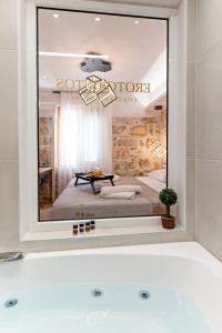 a bathroom with a large mirror over a bath tub at Erotokritos City Luxury Suites in Rethymno