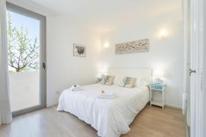biała sypialnia z białym łóżkiem i oknem w obiekcie Sunny Townhouse With Terrace in Son Serra w mieście Son Serra de Marina