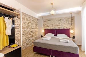 Erotokritos City Luxury Suites في مدينة ريثيمنو: غرفة نوم بسرير وجدار حجري