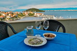 a blue table with a plate of food and two wine glasses at Zadar Kali Booking Franov Residence on island Ugljan with the pool, BBQ and beautiful sea-view! in Kali