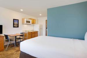 a bedroom with a bed and a table and a kitchen at WoodSpring Suites Charlotte Shelby in Shelby