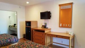 Dormitorio con escritorio, cama y TV en Rodeway Inn Alameda-Oakland en Alameda