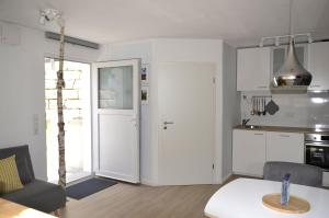 a kitchen and living room with white cabinets and a table at Ferienwohnung Zaunkönig in Beuren