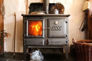 a stove with a fire in a room at Bryngolau in Brechfa