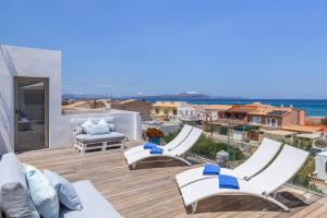 Un balcón con sillas blancas y vistas al océano. en View House with terrace Son Serra Mallorca, en Son Serra de Marina
