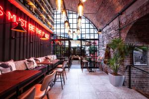 um restaurante com mesas e cadeiras e uma parede de tijolos em The Address Connolly em Dublin