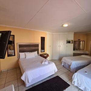 a hotel room with two beds and a flat screen tv at Ethen Guesthouse in Polokwane