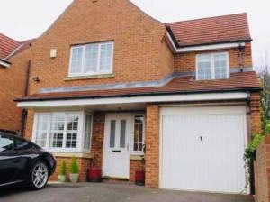 a brick house with two white garage doors at The Pavilion - Stunning, 4 Bedroom House with Free Parking in Wakefield