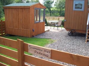 Waterloo Farm Shepherds Hut Glamping with Sun Lounge في بيرث: سقيفة خشبية عليها لافتة مكتوب عليها "موقف سيارات غرباء"