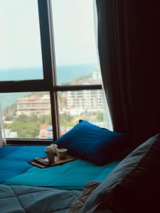 Un dormitorio con una cama y una ventana con una bandeja con una planta en Kuno - 2Br, Beachfront Jomtien en Jomtien Beach