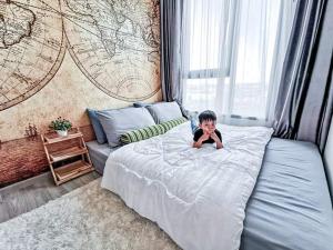 Un niño pequeño acostado en una cama en un dormitorio en Kuno - 2Br, Beachfront Jomtien, en Jomtien Beach