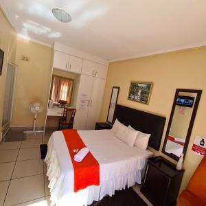 a hotel room with a bed, desk and a television at Ethen Guesthouse in Polokwane