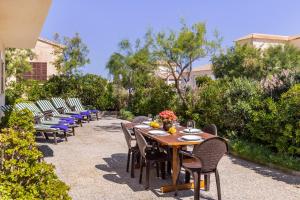a row of chairs and a wooden table with flowers on it at Front Line Beach House Up To 6 Guests in Mallorca in Son Serra de Marina